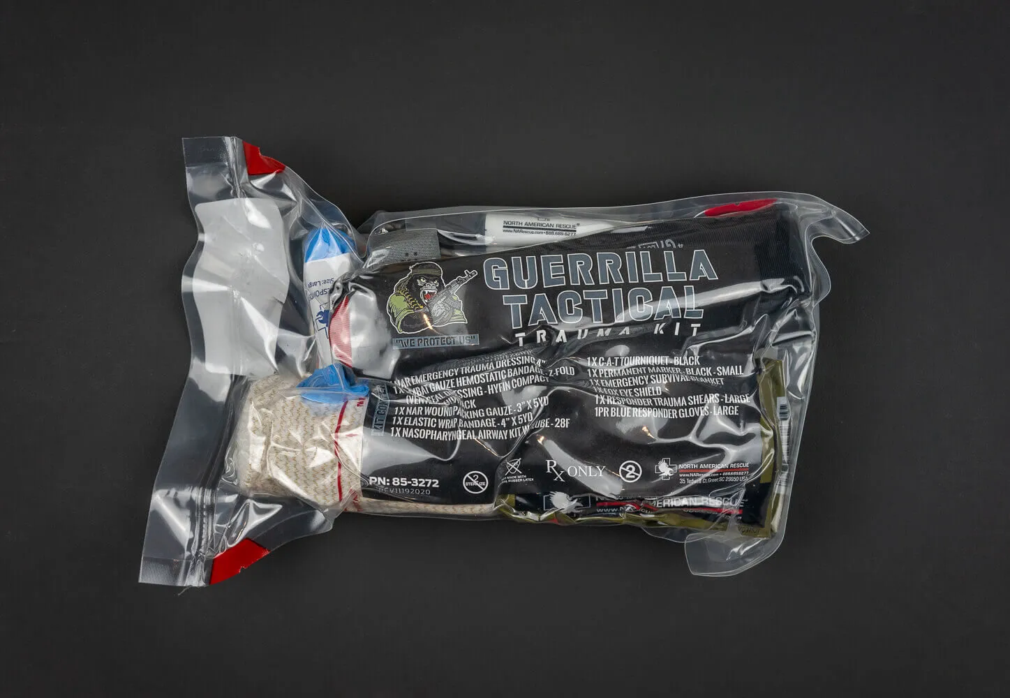 The complete, full-sized Guerrilla Tactical Trauma Kit (GTTK), heavy-duty vacuum-sealed in clear, weatherproof thick plastic. The front insert clearly displays our "We Protect Us" gorilla emblem alongside a comprehensive, itemized list of premium MARCH-compliant trauma contents, including hemostatic bandages, a chest seal twin pack, a nasopharyngeal airway, and large trauma shears packed inside.