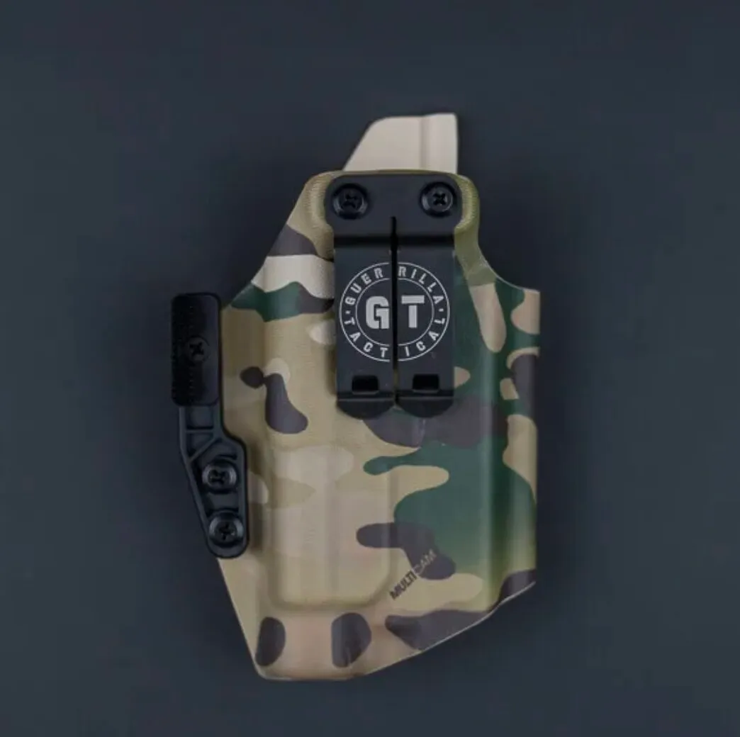 A Low Pro light-compatible inside-the-waistband (IWB) Kydex holster in Multicam camouflage, featuring a centered discrete metal belt clip with the Guerrilla Tactical circular logo and an attached concealment wing.
